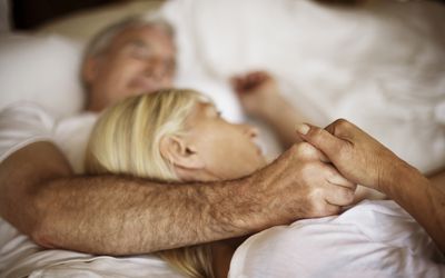 A mature couple embraces in bed